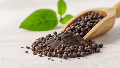 Black peppercorns and ground powder with a wooden scoop and leaf