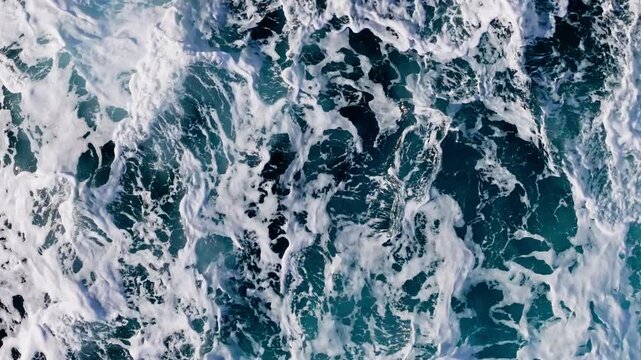 Top aerial view of turbulens water sea waves splashing with white foam, water rolling and creating foam patterns