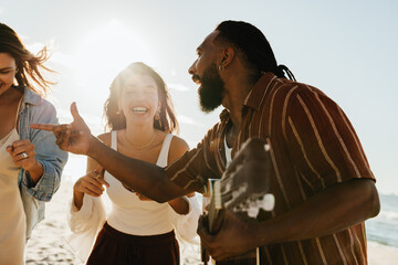 Friends enjoying music and laughter on a sunny beach day