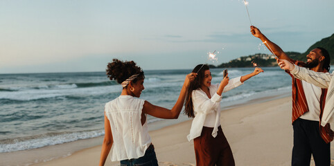 Group of friends celebrating with sparklers on a beach during sunset