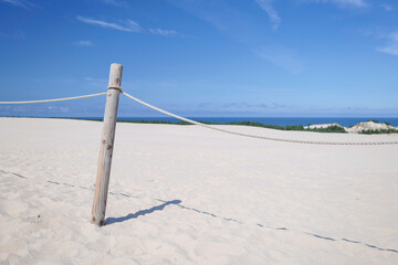 Fencing of the dune area. A protective barrier constructed of a round wooden post and ropes. Designating a no-cross zone. Dunes. Baltic Sea. Leba, Poland.