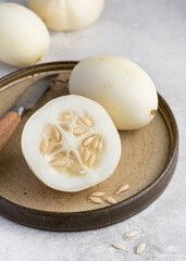 Unique heirloom Crystal Apple (Cucumis sativus) cucumber is shown sliced open, displaying its crisp interior on a rustic plate. Concepts for organic produce, home gardening, healthy eating.
