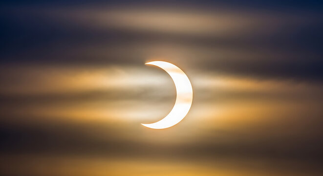 Stunning crescent solar eclipse against a vibrant colorful sky.