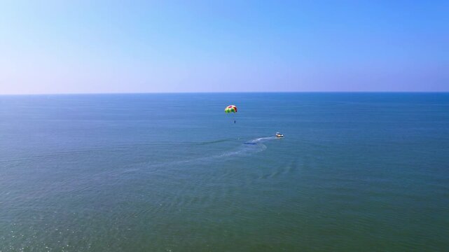parasailing with boat in Arabian Sea at colva beach. day time, push in shot, drone shot, 4k.