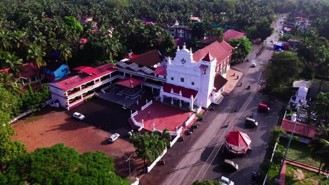 Our Lady of Merces Church with coconut trees and road at colva, south goa, india. day time, push back shot, drone shot, 4k.
