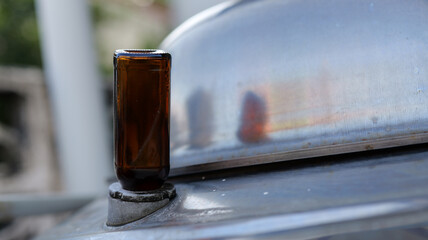 Close-Up of Brown Glass Bottle on Metal Surface with Reflections and Industrial Background