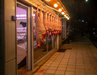 Night showcase of a butcher shop with hanging carcasses of sheep and goats in Greece 