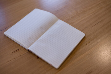 Open lined notebook on wooden table with blank pages, perfect for journaling, note-taking, writing, studying productivity-themed content.