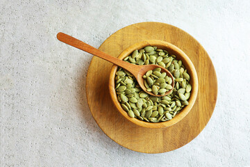 Pumpkin seeds. Green peeled pumpkin seeds in wooden bowl on white background, copy space, banner.