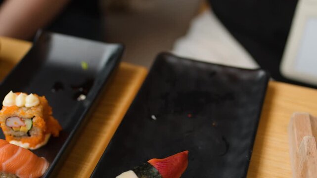 Hand Picking Up Tamago Nigiri From Sushi Plate at Table