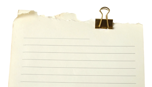 Torn, lined paper held by a brass clip against a black backdrop
