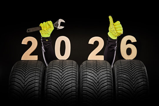 Winter car tires service and thumbs up hands of mechanic and text 2026 happy new year on black background