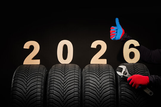 Winter car tires service and thumbs up hands of mechanic and text 2026 happy new year on black background