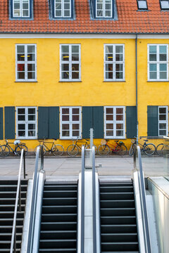 Urban architecture in Copenhagen combining an escalator with a yellow facade and window detail to create movement, contrast and precision within a dynamic exterior view for visual communication