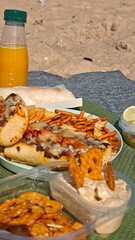 Picnic spread with baked sandwiches, snacks and orange juice set on a blanket at the beach. this image conveys leisure, outdoor picnic and relaxed summer enjoyment