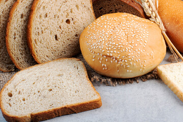 Assortment of Fresh Bread Slices and Sesame Seed Bun on Rustic Jute Background