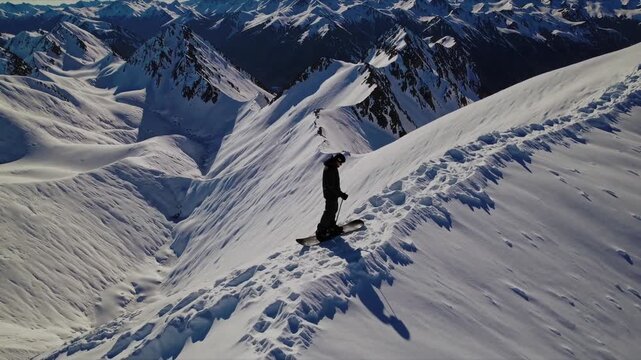 Mountain Conqueror: A lone figure fearlessly navigates a snowy mountain ridge, etched with footprints, symbolizing courage and adventure against a backdrop of majestic peaks.