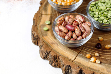 Assorted Raw Beans, Dried Peas, and Corn Kernels in Small Glass Bowls on a Wood Slab