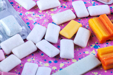 Assorted Chewing Gums in Vibrant Colors and Blister Packs on a Pink Background