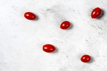 Scattered Red Cherry Tomatoes on a Minimalist White and Gray Textured Background