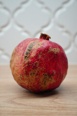 A ripe pomegranate fruit on a wooden surface with a decorative background