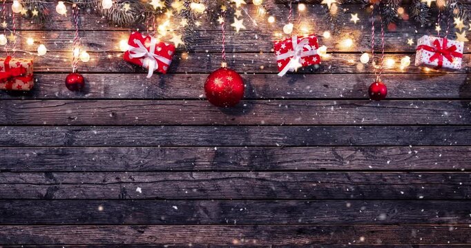 Cozy Christmas decorations arranged on rustic wood with gentle falling snow creating a festive winter atmosphere. Ideal as a holiday background or seasonal backdrop.