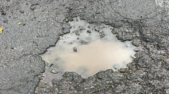 A large pothole in a tarmac road 