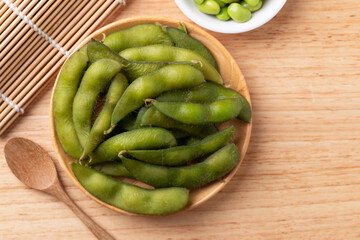 Boiled Edamame beans (Japanese soybeans) on wooden background, Table top view