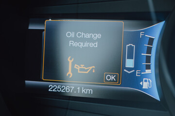 Digital Car Dashboard Displaying Oil Change Required Maintenance Warning with Wrench and Oil Can Symbol, Odometer Mileage, Fuel Gauge, and Headlight Indicators