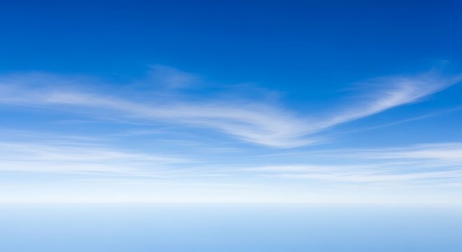 Expansive vibrant blue sky with delicate white wispy clouds stretching across the horizon, peaceful day atmosphere