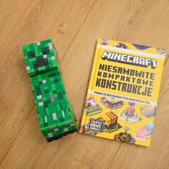 Naklejka premium Minecraft Creeper figure and book on a wooden surface
