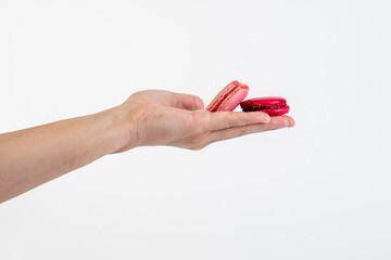 Pink and red macarons in hand on white background
