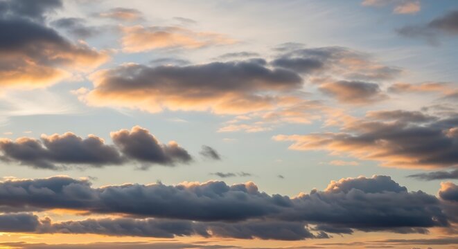Dramatic golden hour sky with scattered cumulus clouds illuminated by warm sunrise light, tranquil nature scene background.