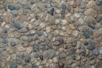 A textured background of river stones and gravel poured with cement. Natural, durable surface. Perfect for texture or street design.