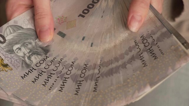 Kyrgyzstan som money holding. Woman hands counting a stack of banknotes. Kyrgyz KGS paper cash. Concept of income, success, business, tax, economy and finance