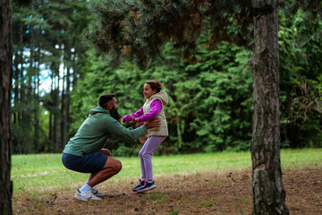 Fototapeta premium Father and daughter playing in the woods, embracing joyful moments
