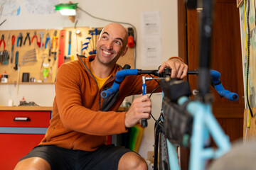 Man cyclist repairing bicycle handlebar in home workshop