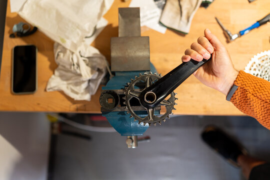 Hand holding bike crankset in a vise for maintenance - Powered by Adobe