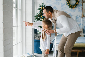 Father And Son Looking Out Window At Christmas
