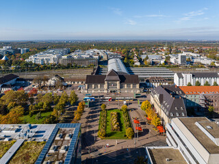 Aerial view of the central station with its sharp angles contrasting with the soft hues of autumn trees, Darmstadt Hauptbahnhof, Darmstadt, Hessen, Germany.