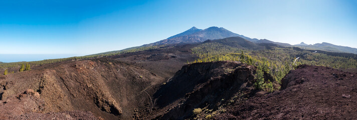Wide panoramic view on volcano Pico del Teide with snow spots from hiking trail Samara. Mountains and lava fields with pine tree forest. El Teide National Park, Tenerife, Canary Islands, Spain