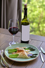 
asparagus in dough with meat on a plate on the table with a bottle of wine