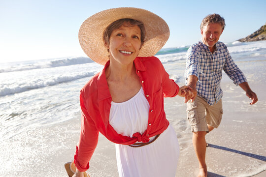 Date, travel and holding hands with couple at beach for summer vacation, romance and connection. Bonding, anniversary getaway and walk with mature man and woman outdoor for holiday, marriage and love