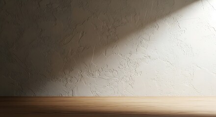 Empty room with a wooden floor and a textured plaster wall illuminated by a diagonal beam of sunlight.