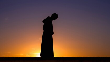 Contemplative monk silhouette against vibrant orange sunset sky creating powerful spiritual meditation scene