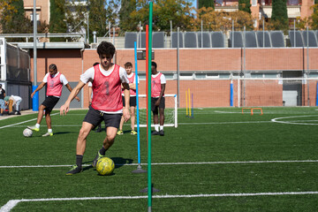 Young men training soccer dribbling on football pitch