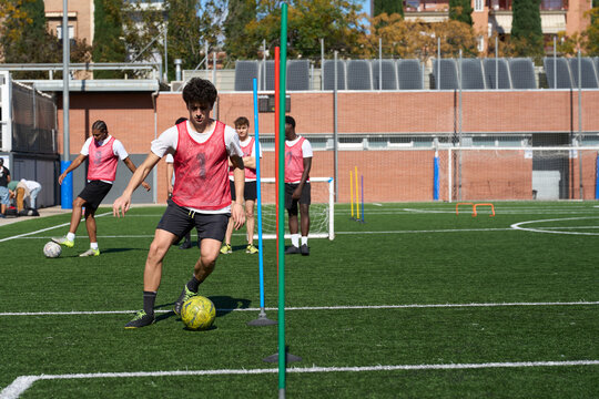 Young men training soccer dribbling on football pitch