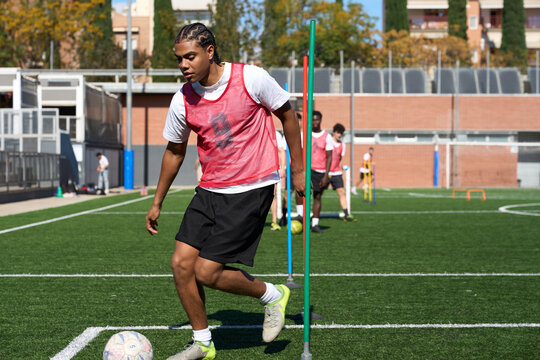Young male soccer player dribbling ball during training drill - Powered by Adobe