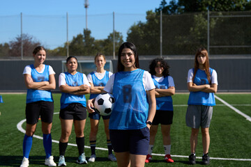 Women's soccer team posing on football pitch