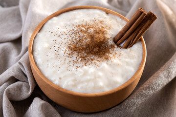 Rice pudding with cinnamon in wooden bowl